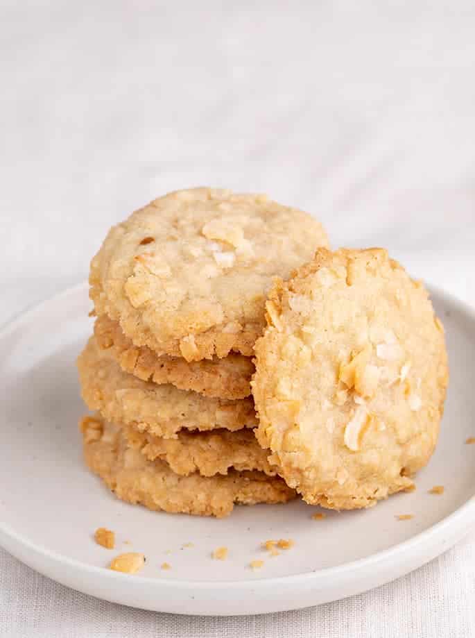 Stack of 5 coconut cookies with one on its side on a small white plate