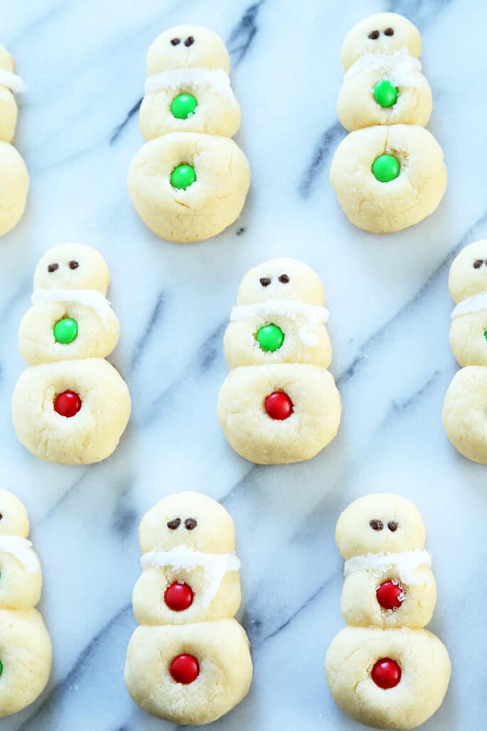 Overhead view of snowman sugar cookies on a marble surface 