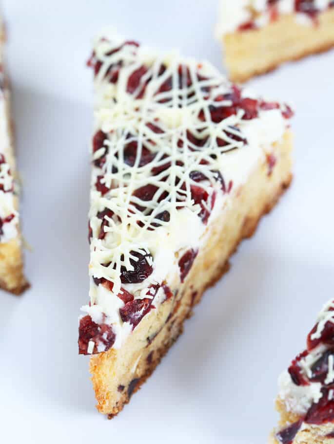 A close up of a cranberry bliss bar on a white surface 