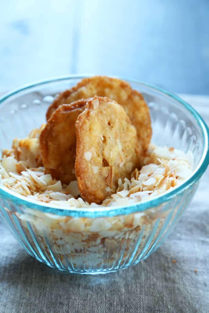 A bowl of with coconut chips and 3 coconut cookies 