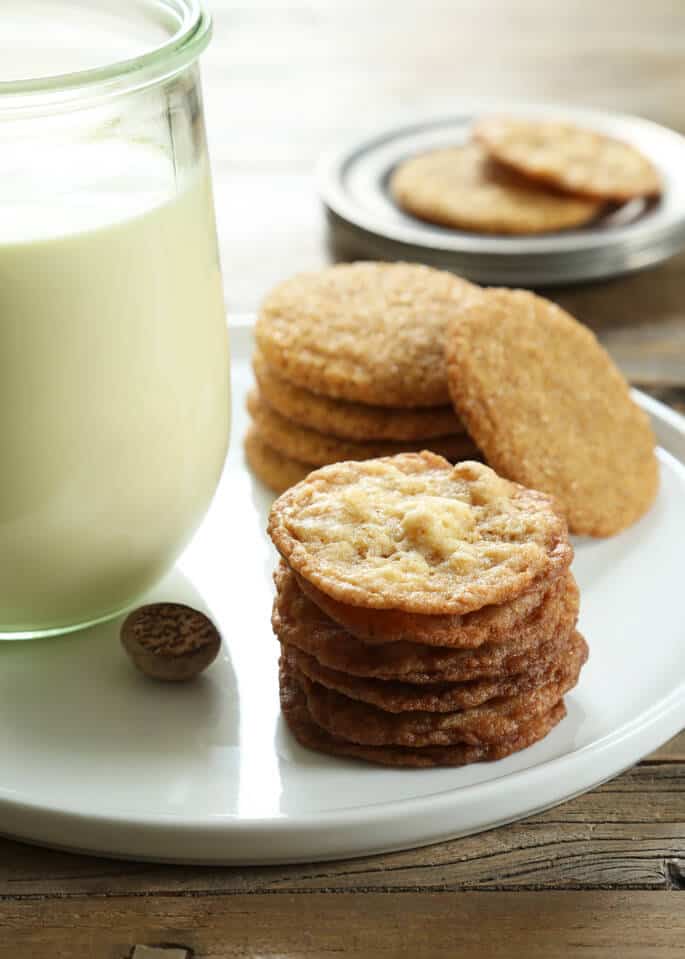 Stack of cookies on a plate with a jar of egg nog 