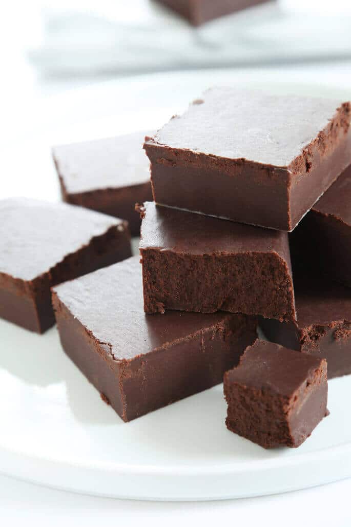 A stack of chocolate vegan fudge on a white surface