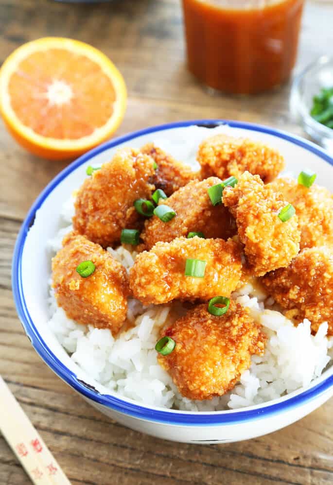 Overhead view of Chinese-style orange chicken with rice in a white bowl