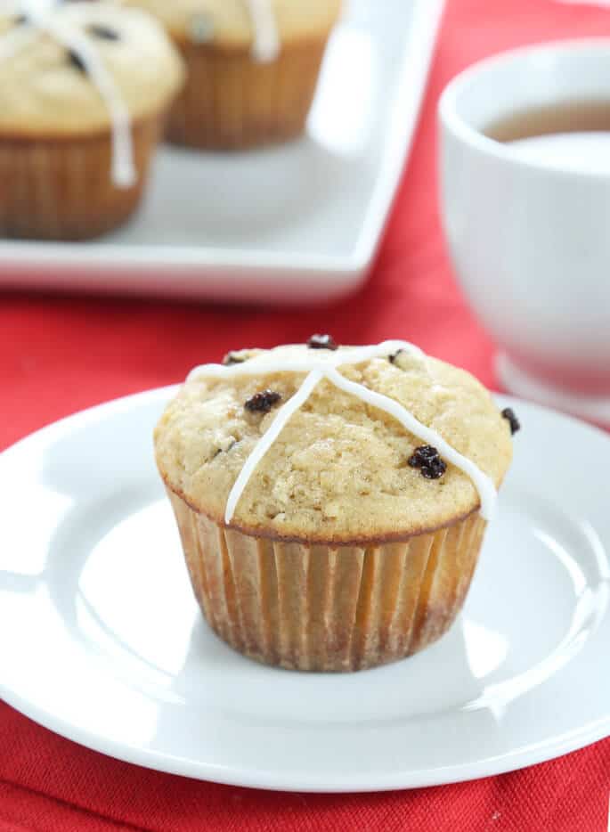 Hot cross bun with frosting on a white plate 