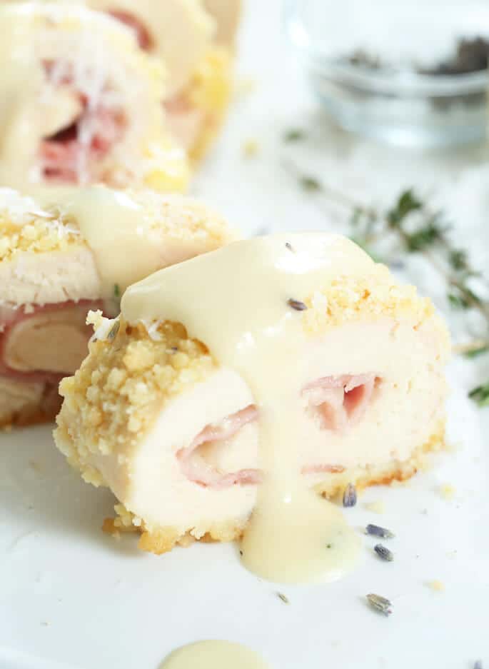 Chicken Cordon Bleu close up with white sauce on a white plate 