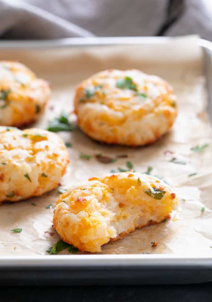 Gluten free cheddar bay biscuits on a tray with a bite taken from one