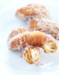 A close up of inside of cinnamon sugar biscuit donut twist on white plate