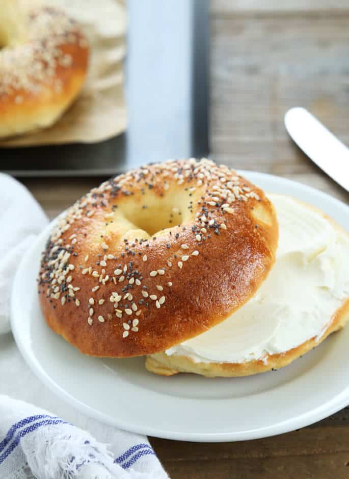 A bagel with cream cheese on a white plate