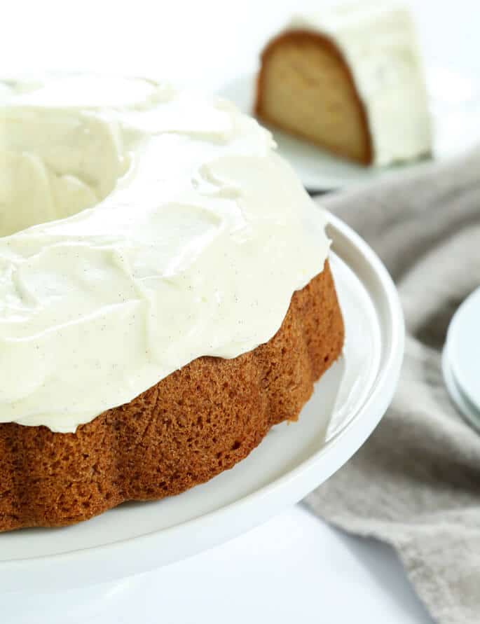 A side view of vanilla crazy cake with vanilla frosting on a white plate