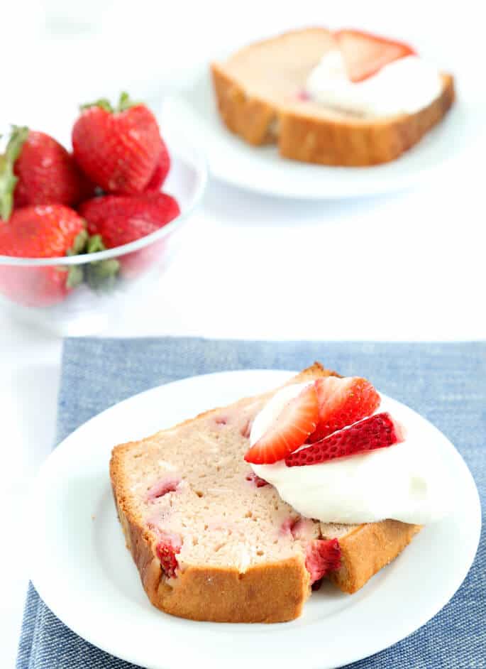 Strawberry bread with strawberries and whip cream on a white plate