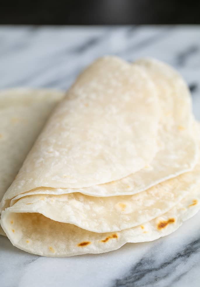 3 burritos folded in half on marble