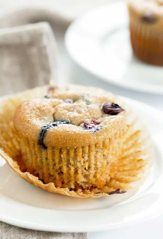 A close up of a muffin with blueberries on a white plate 