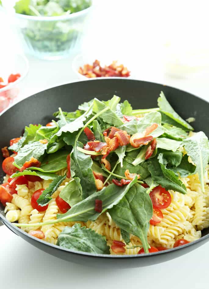 Arugula leaves on a bowl of BLT pasta