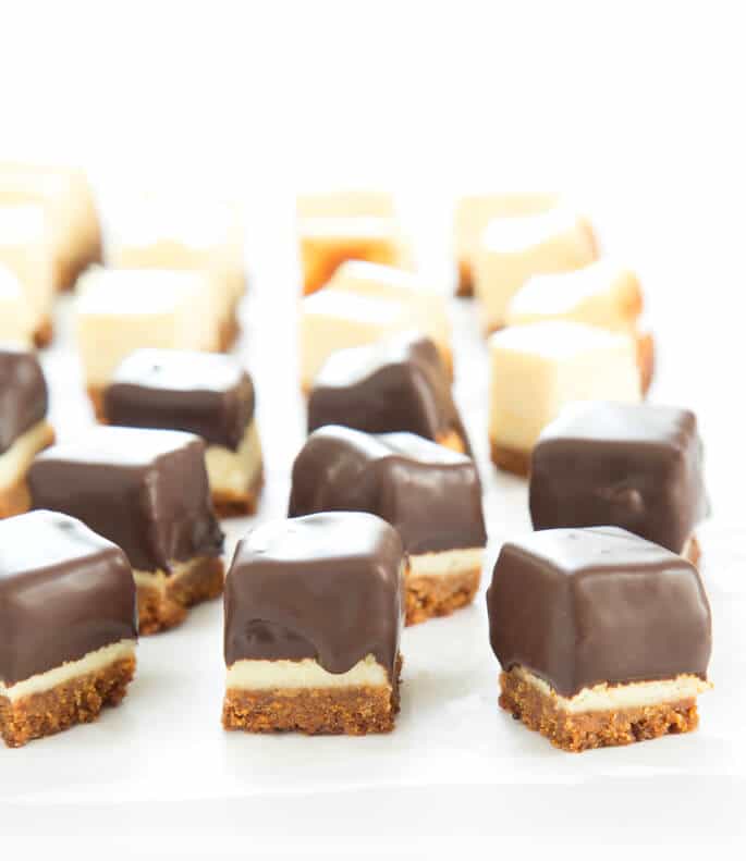 Squares of cheesecake half with chocolate coating and half without