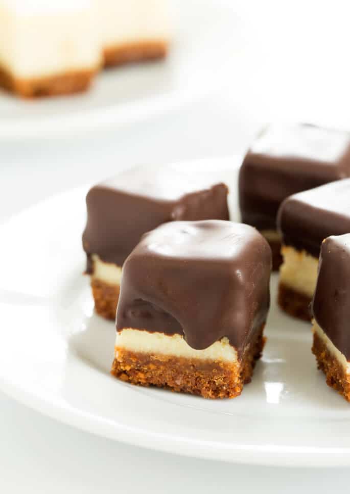 A close up of chocolate covered cheesecake squares on a plate