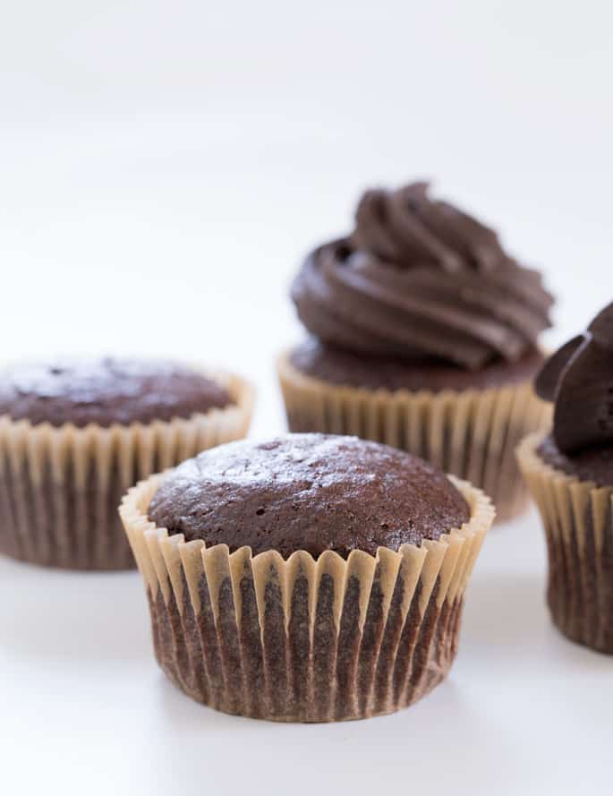 A close up of 4 chocolate cupcakes on a white surface