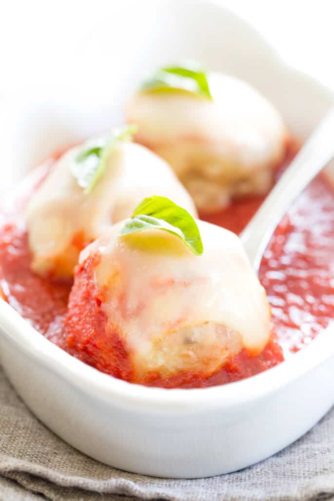 A close up of a white platter with chicken farm meatballs being scooped out of platter