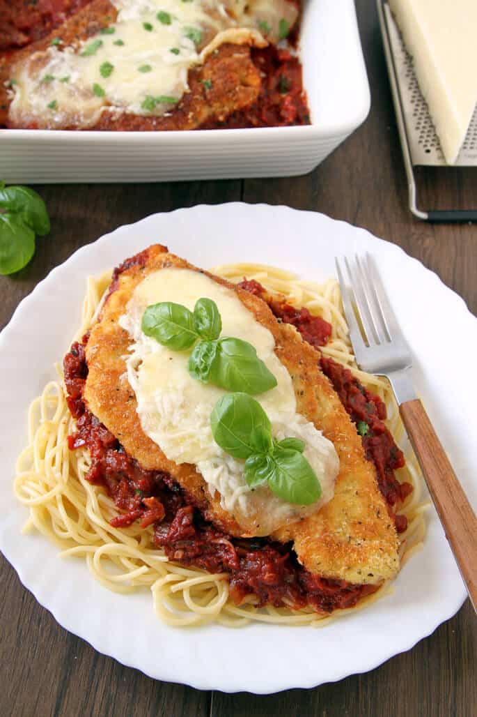 Regular overhead view of chicken parmesan, red sauce, and spaghetti on white plate 