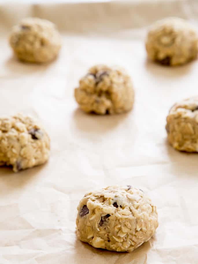 Raw disks cookie dough with oats and chocolate chips on brown paper