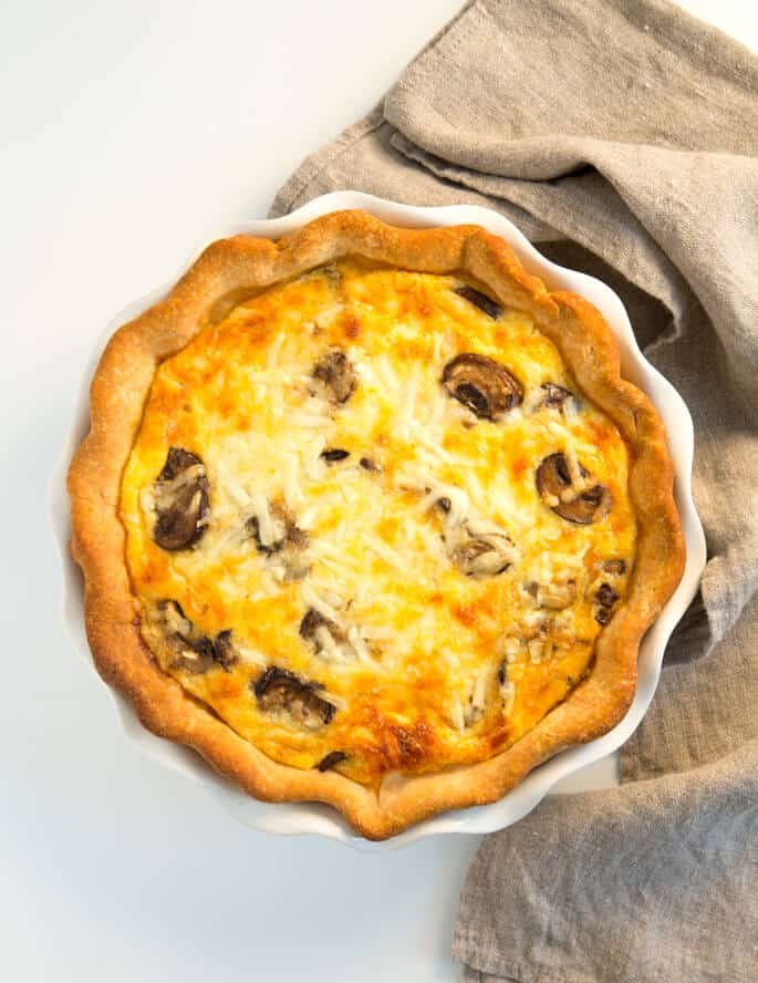 Overhead view of quiche on white surface with brown towel