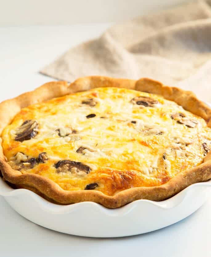 Close up quiche on white baking tray on white surface 