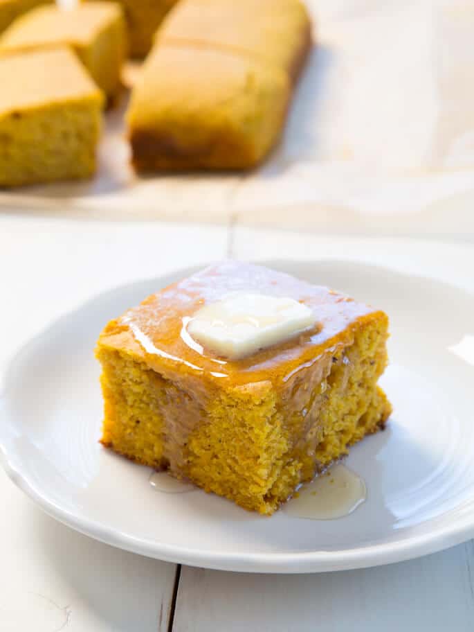 A close up of the side of a pumpkin cornbread piece on a white plate 