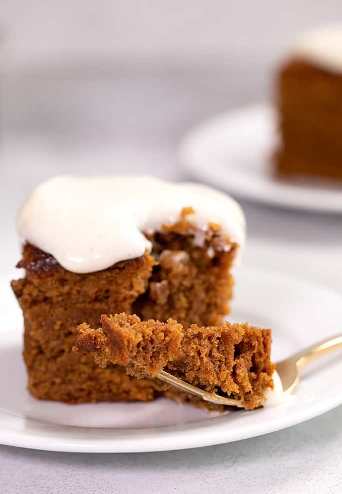 Closeup image of forkful of gingerbread cake on small white plate