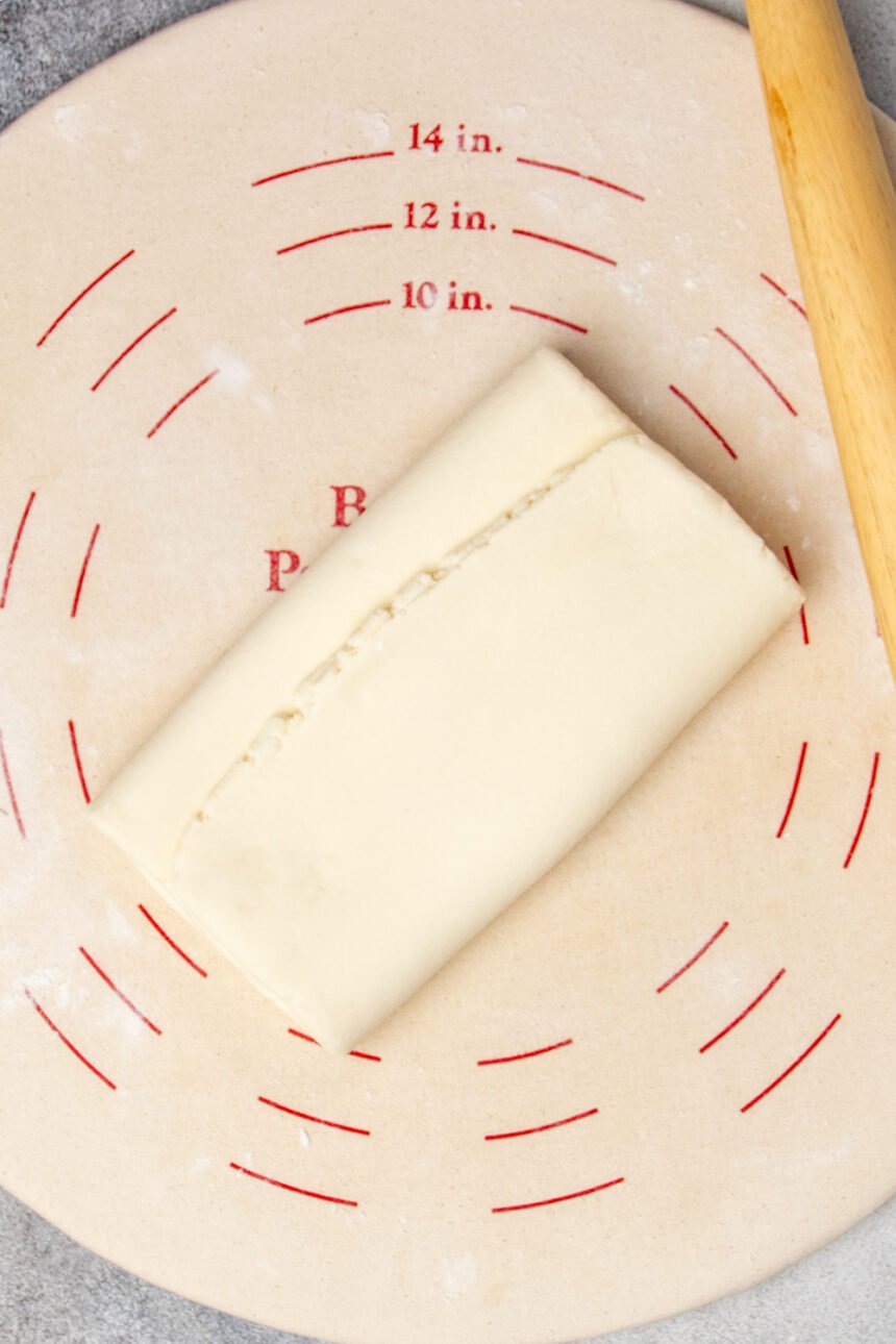 light tan pastry dough rolled out and folded in thirds like a business letter on light tan pastry board