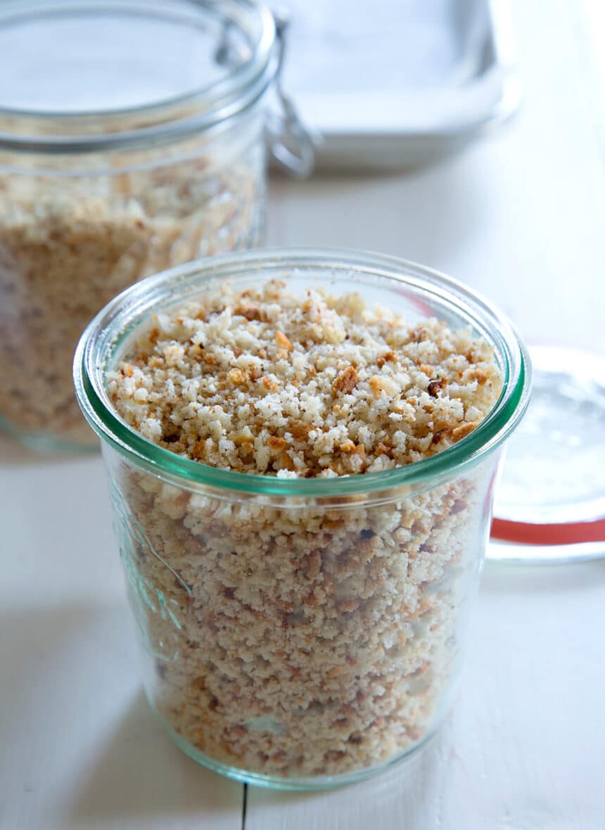 Glass jar of gluten free bread crumbs on white surface