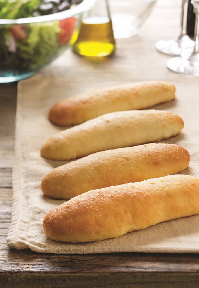 A row of breadsticks on beige towel