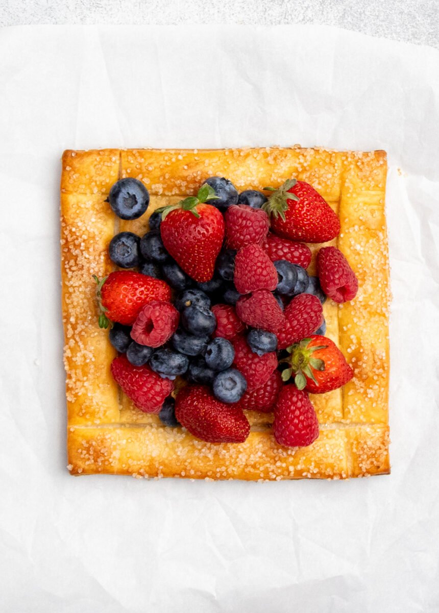 Overhead image of gold brown puff pastry square with strawberries, blueberries and raspberries in center