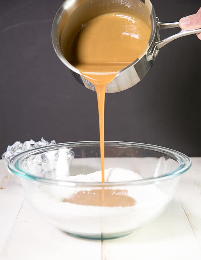 Melted peanut butter being poured into bowl of dry ingredients