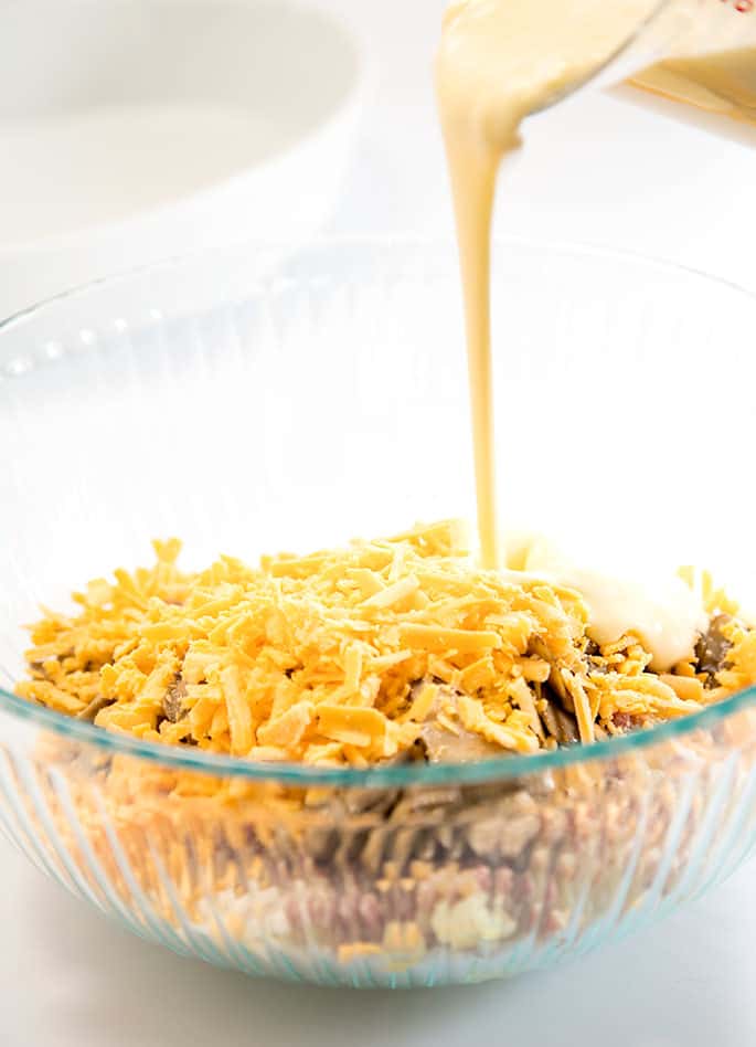 Beaten eggs being poured into bowl with cheese