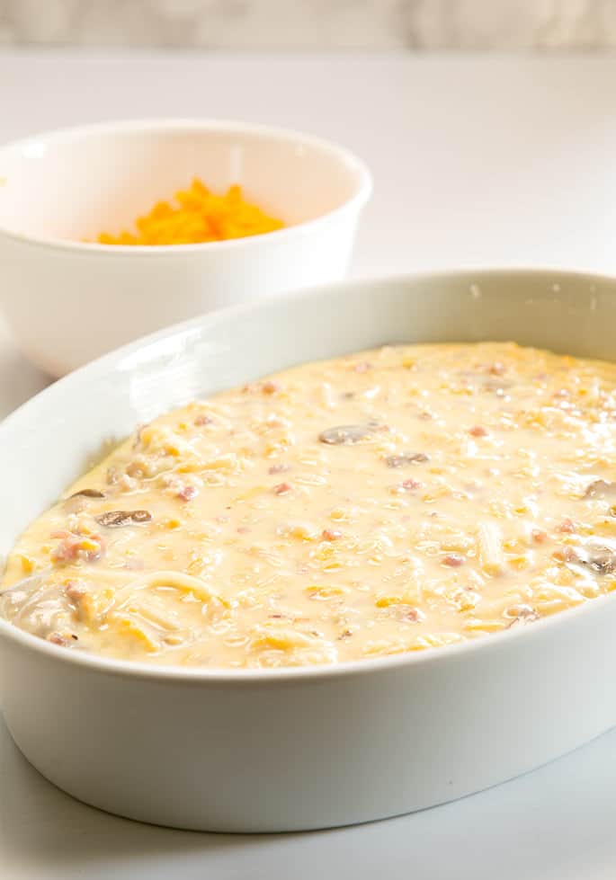 A bowl of cheese in background with platter of breakfast casserole.