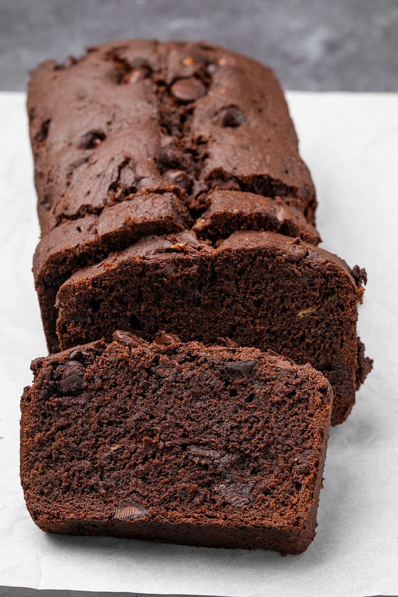 Brown quick bread loaf sliced 3 times on white paper