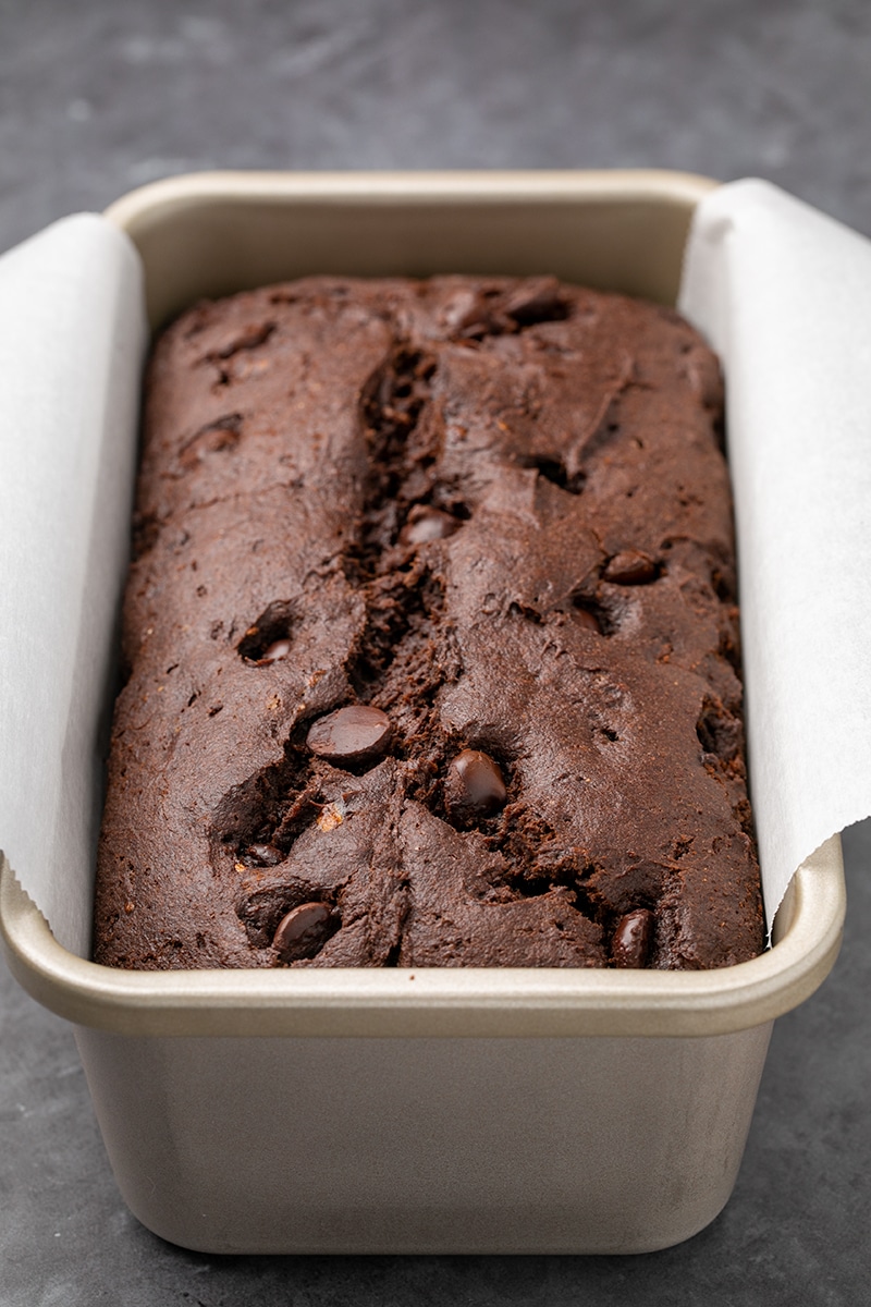 Dark brown cake in a white paper lined metal loaf pan