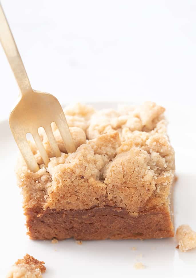 Fork stuck in square of coffee cake on a white plate