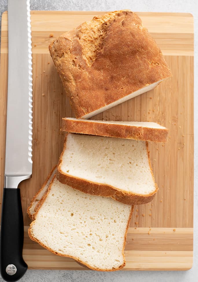 English muffin bread loaf partially sliced on a cutting board overhead image