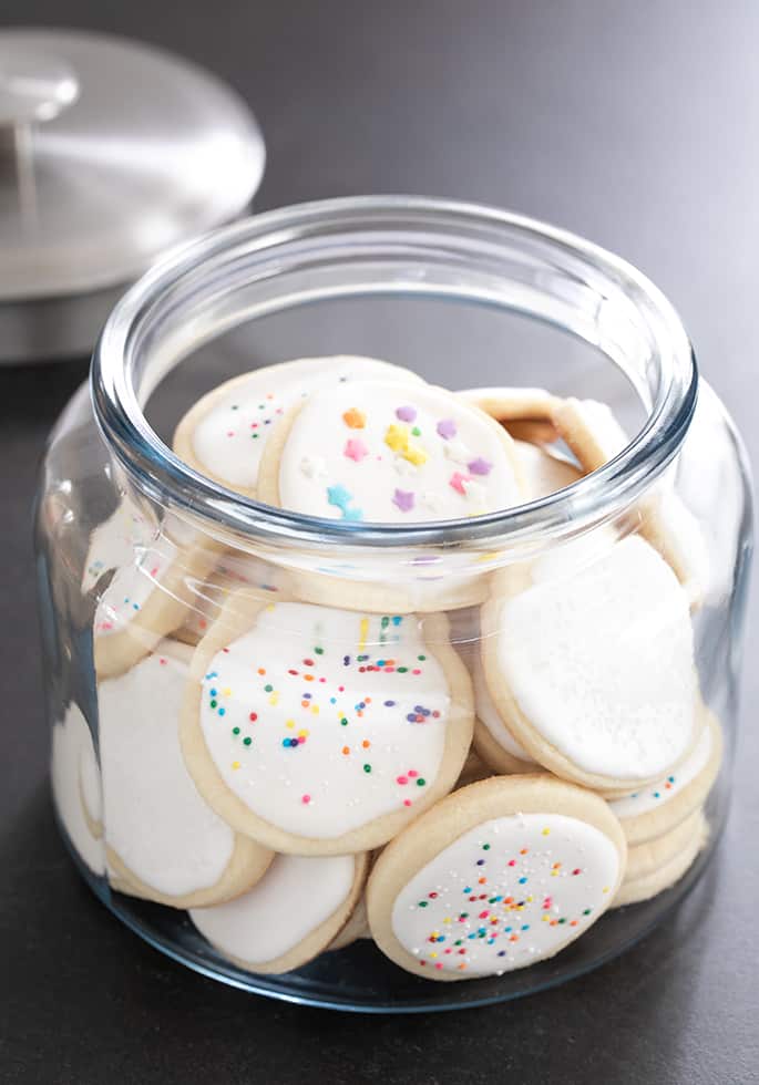 Gluten free soft cutout sugar cookies with royal icing, stored in a large glass jar.