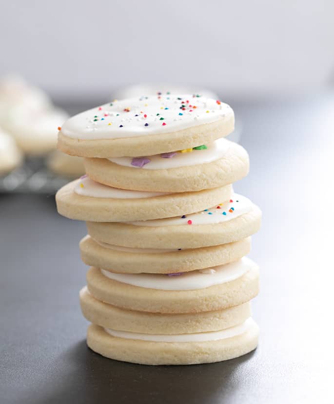 Gluten free cutout sugar cookies with royal icing and sprinkle decorations, in a tall stack.