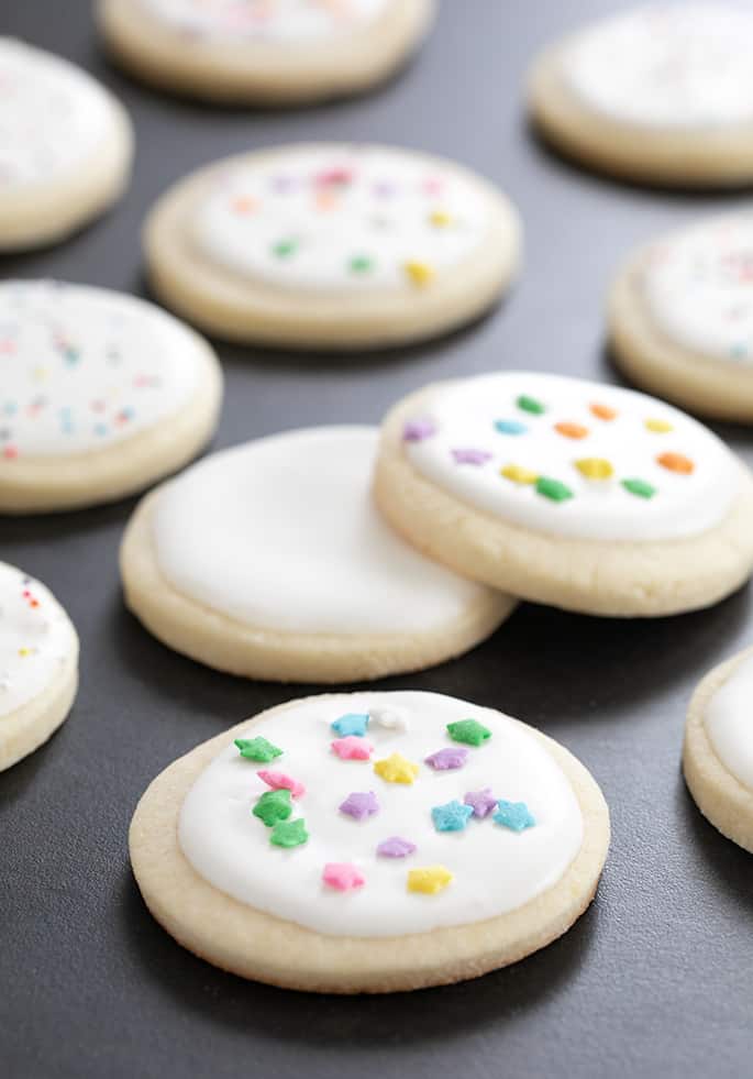 Close up of sugar cookies on a dark surface.