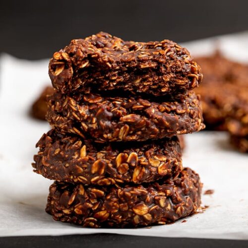 Stack of 4 chocolate oat cookies on white paper, top cookie broken