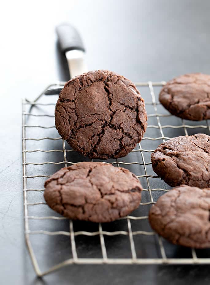 Double chocolate cookies on a wire rack with one cookie on its side