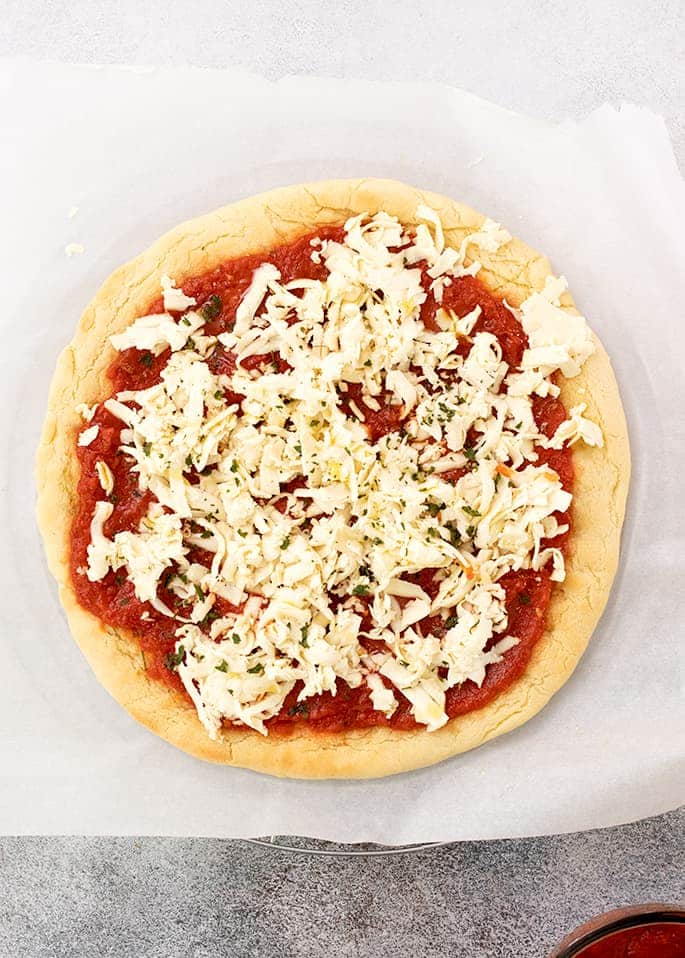 Overhead image of parbaked paleo pizza crust with raw toppings