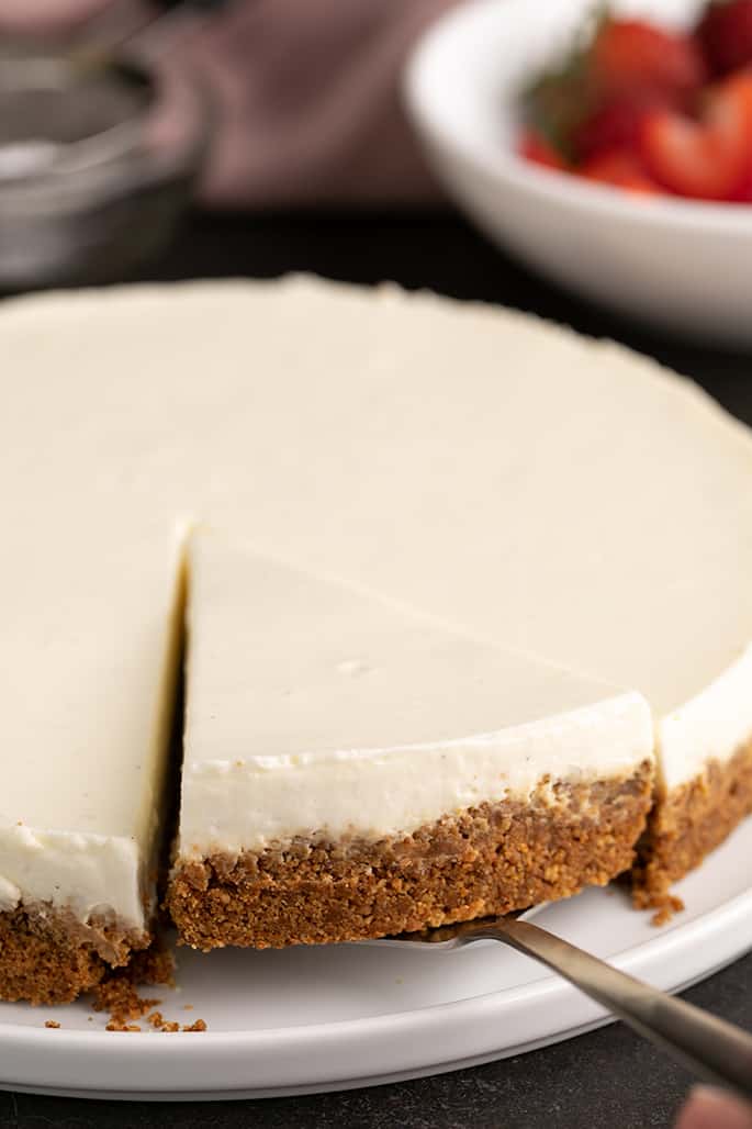 slice of no bake cheesecake being removed from rest of cake with a metal spatula