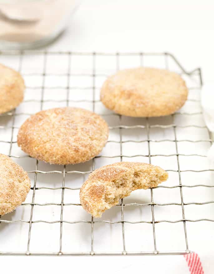 gluten free snickerdoodles cookies on wire rack with one cookie broken in half