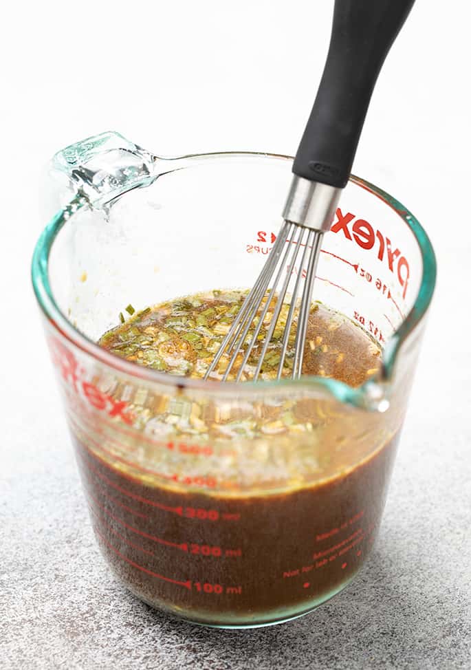 2 cup glass measuring cup with brown sauce and whisk