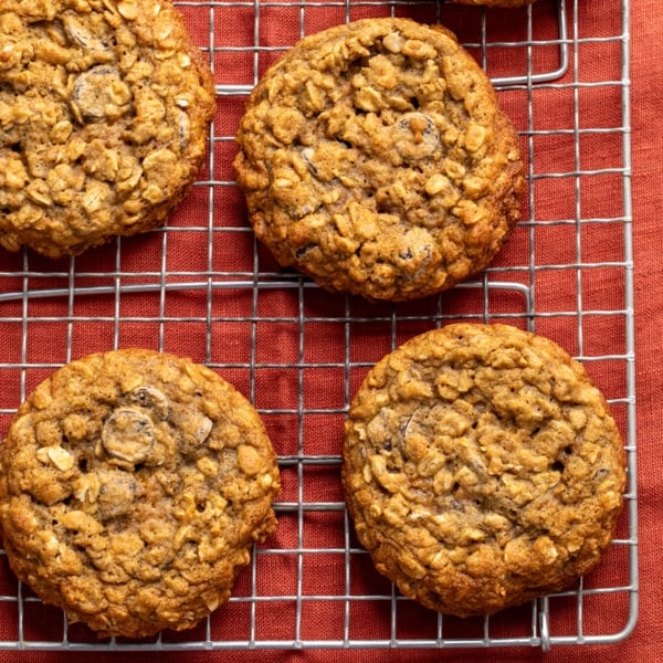 closeup of 4 round brown cookies on a wire rack on a red cloth