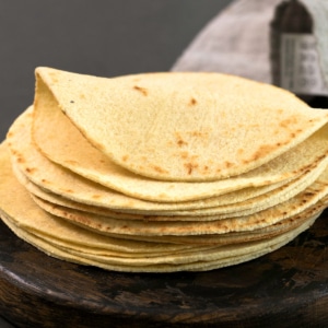 Stack of low carb almond flour tortillas on brown wood surface