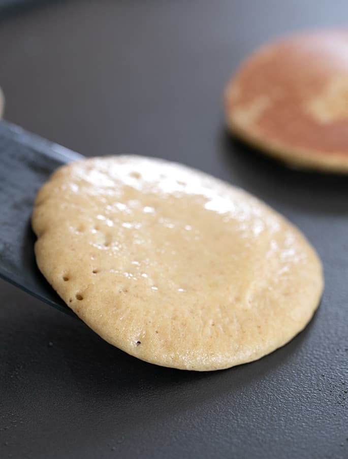 Protein pancakes being flipped on a griddle